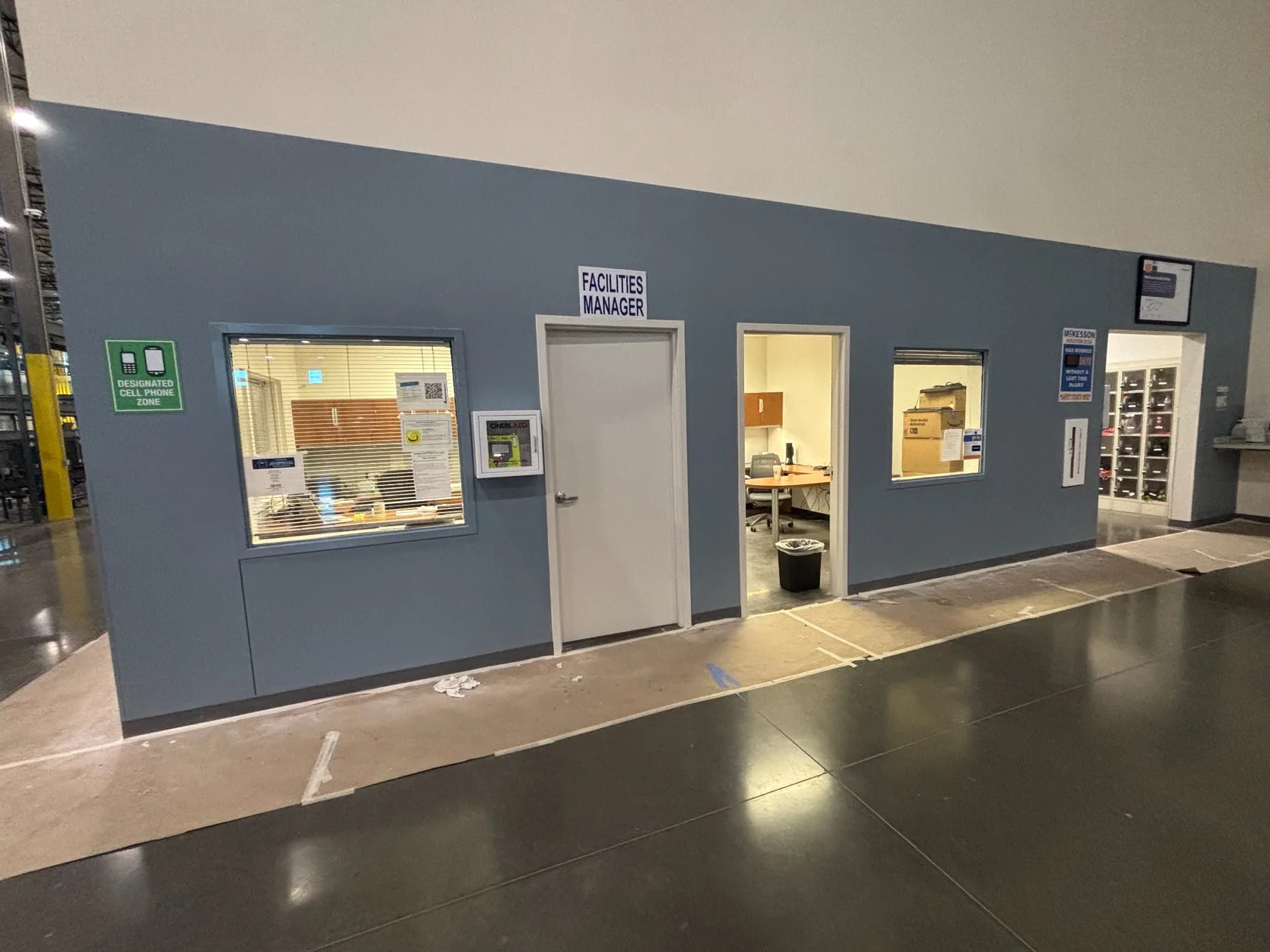 Blue painted office enclosure wall with doors and windows inside the McKesson Medical warehouse in Houston, Texas.